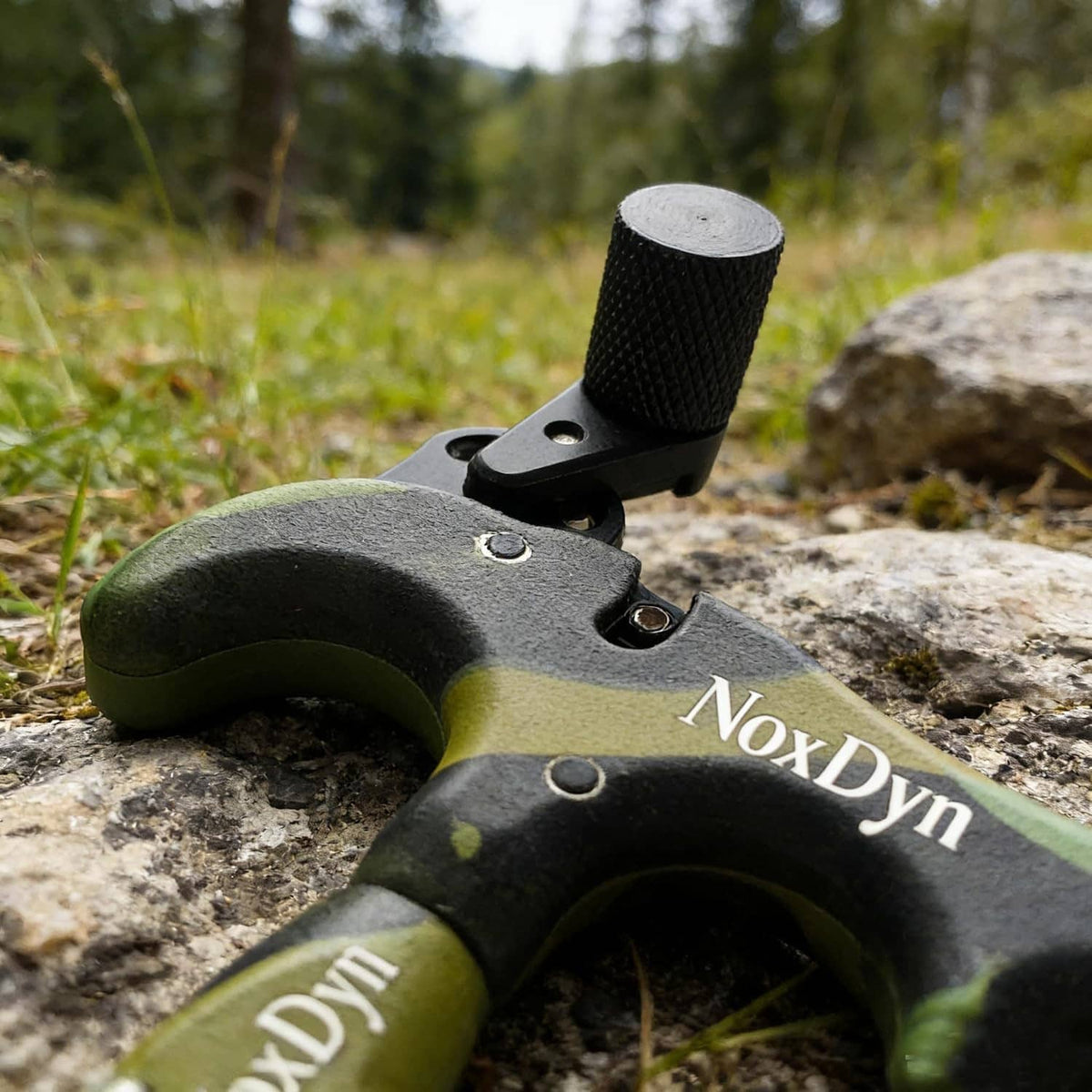 Archery thumb release on camo green/black body, black handle, NoxDyn metal jaw