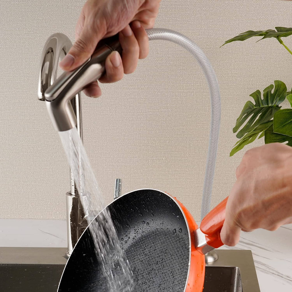 Brushed nickel sprayer head releasing water over sink