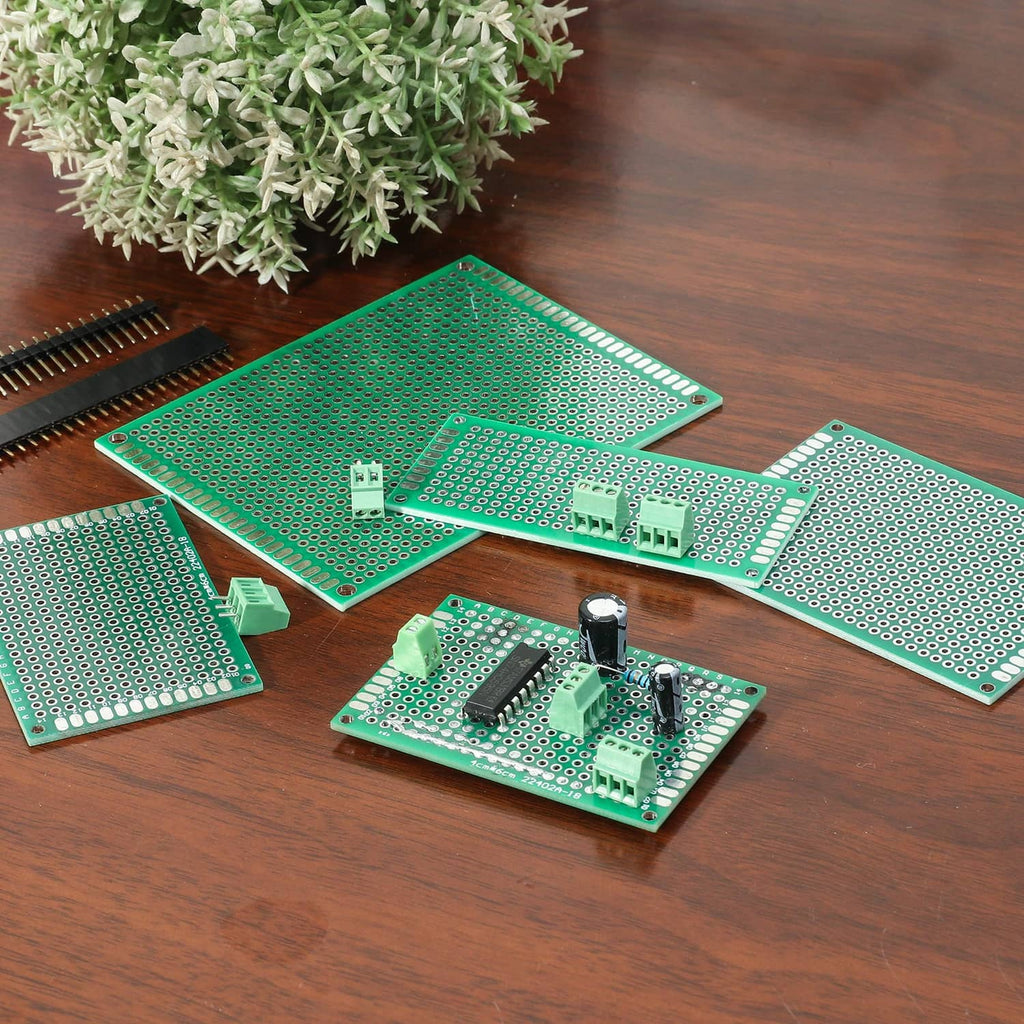 Assorted green PCB prototyping boards with mounted components on wooden surface