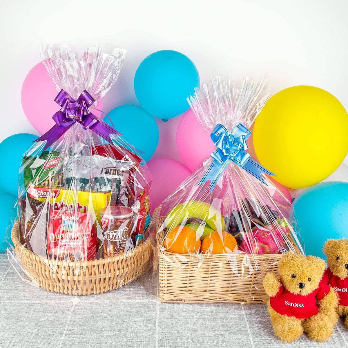 Two clear cellophane basket bags with purple and blue bows, wicker baskets with treats.