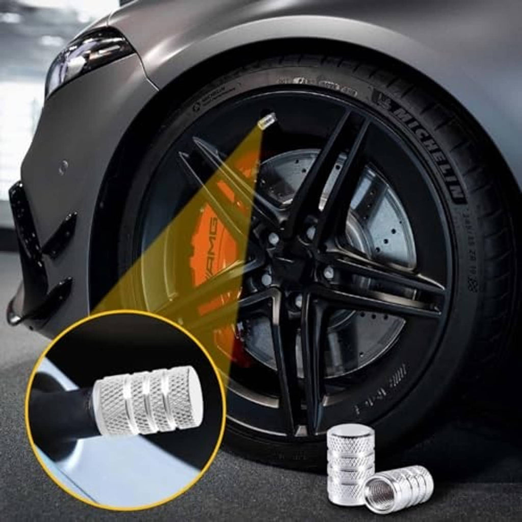 Silver tire valve stem cap with knurled sides, shown near a tire valve