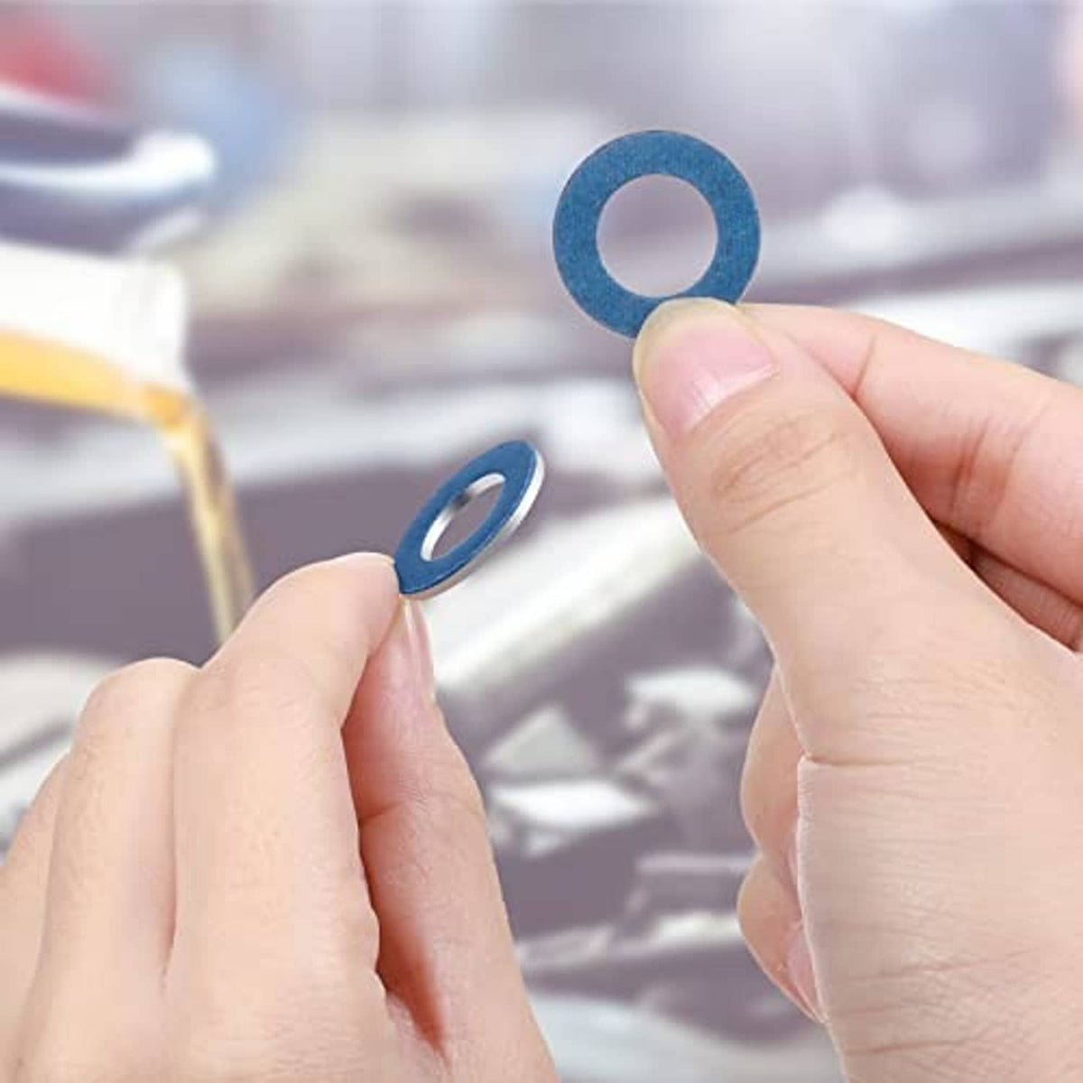 Hand holding a blue metal crush washer ring with center hole for sealing