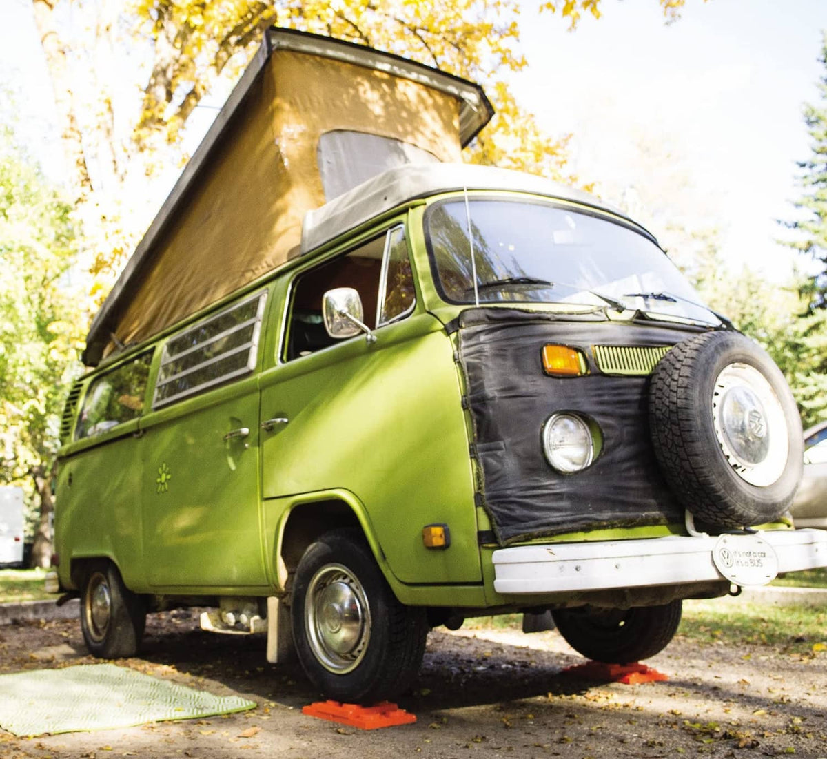 Orange RV leveling blocks on pavement under a green van