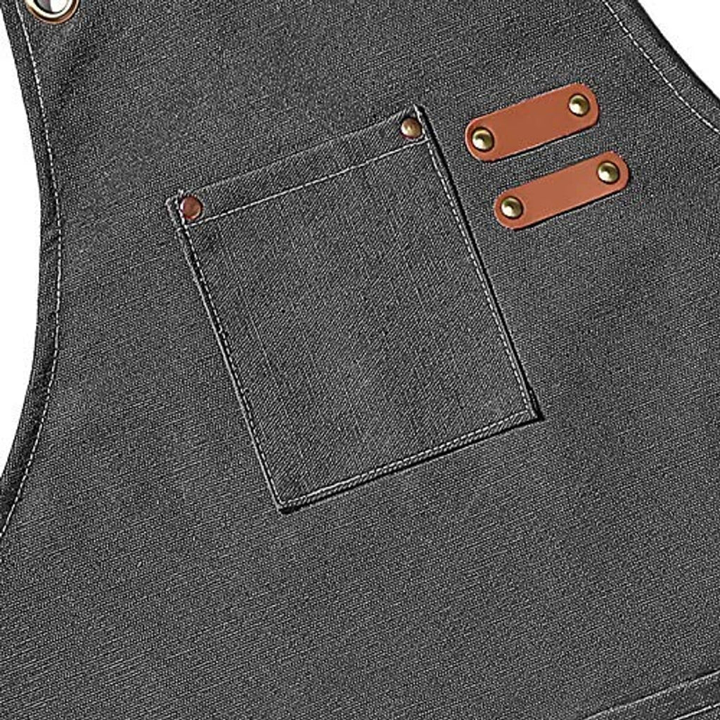 Grey apron chest pocket detail with two-tone leather buckle tabs