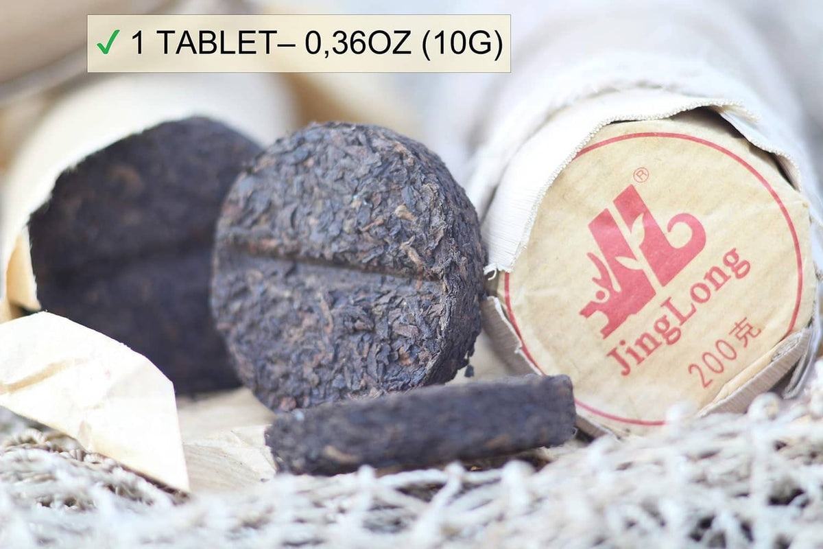 Pu-erh tea tablets with bamboo leaf tube end, resting on white paper filler