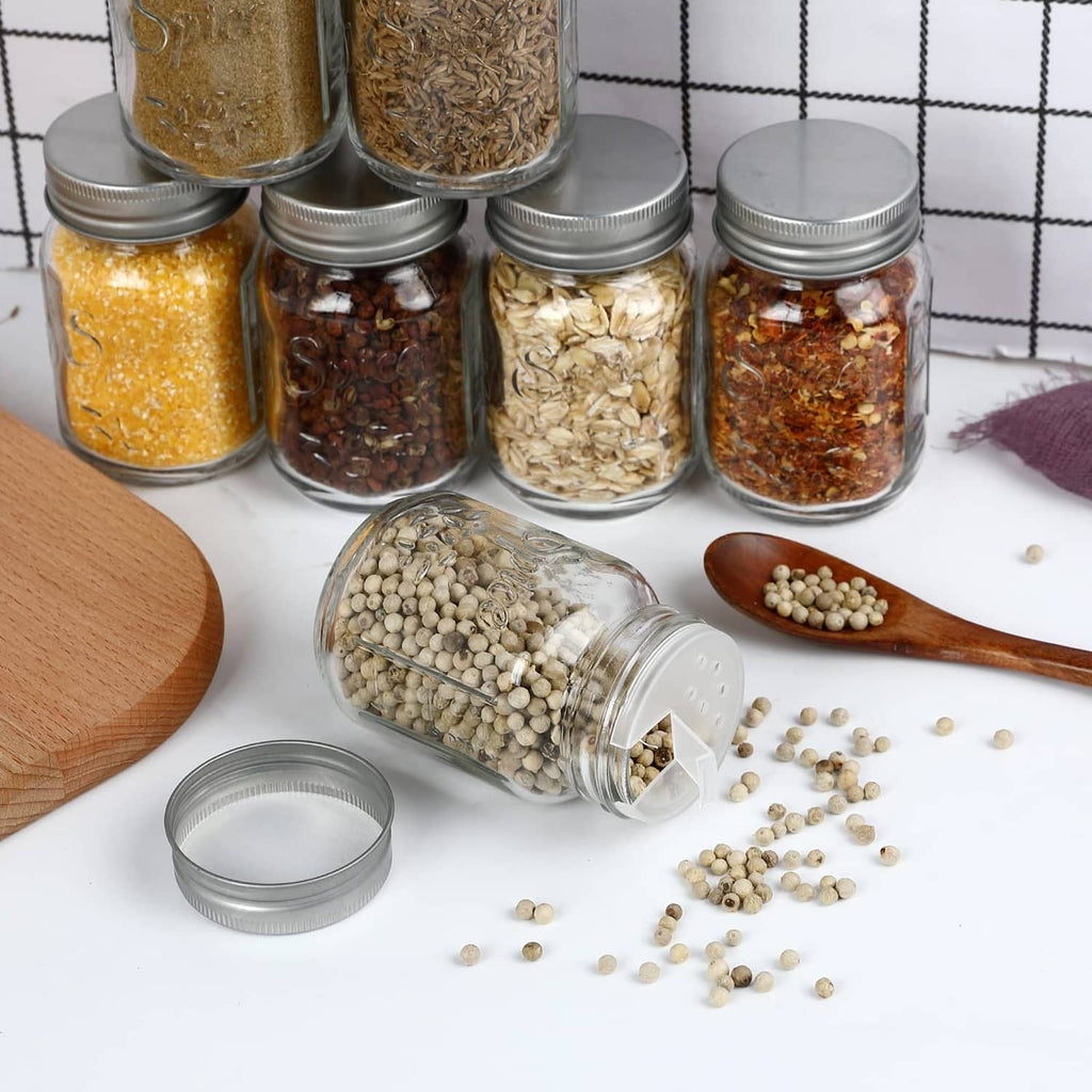 Clear glass spice jars with silver lids, with scattered spices and open jar lid