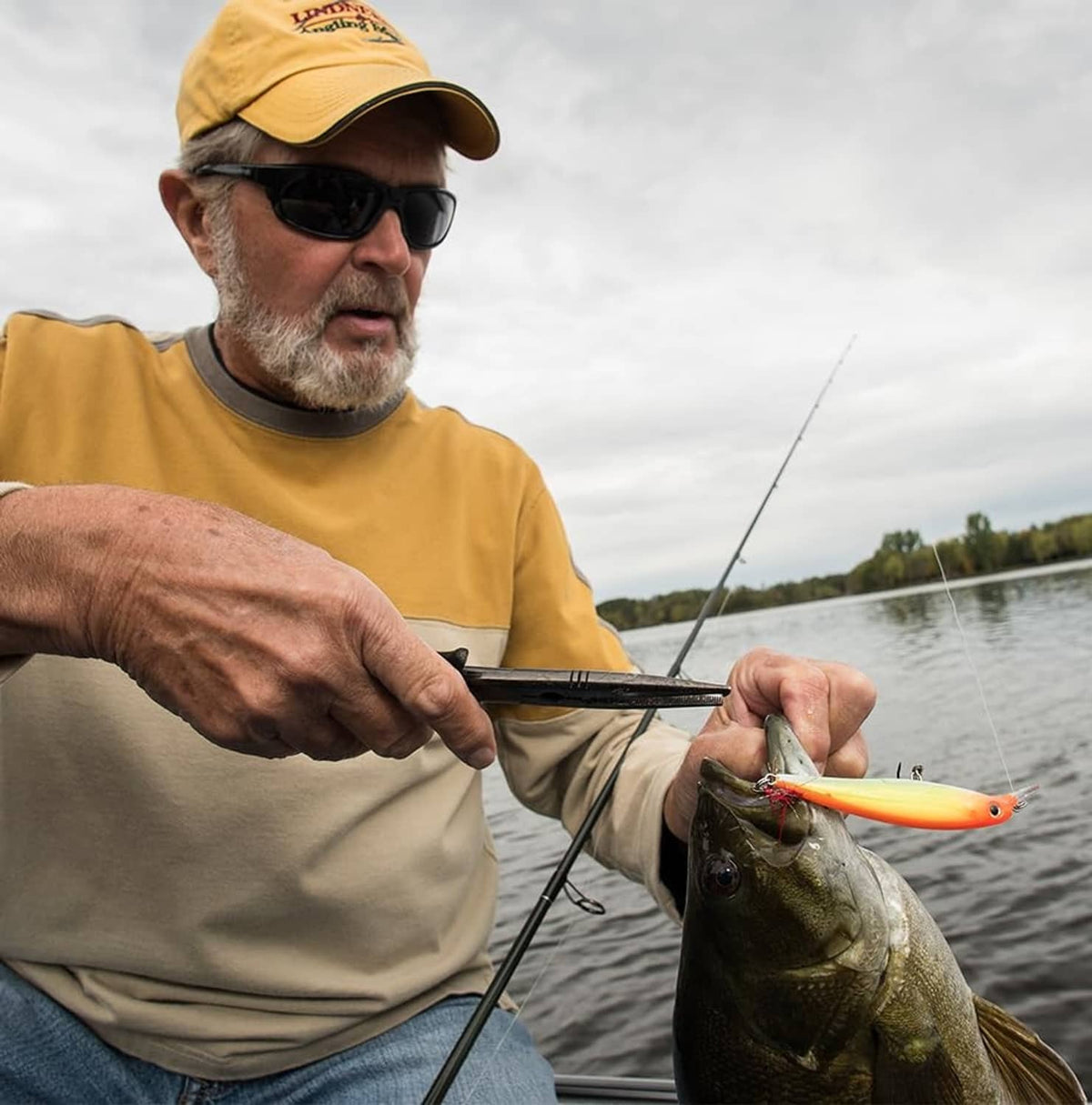 Orange suspending jerkbait with treble hooks, in angler's hand