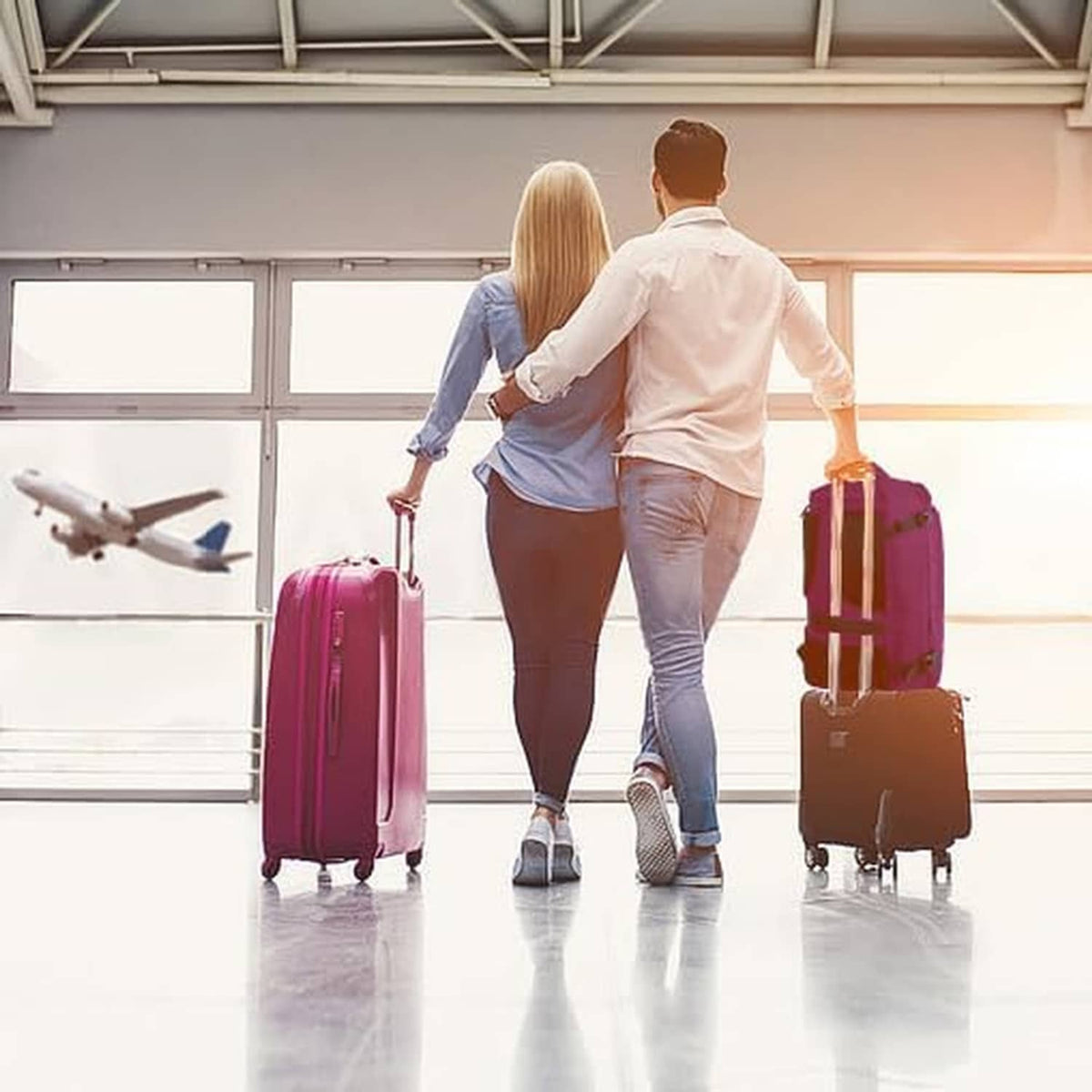 Purple travel backpack carried by travelers beside rolling suitcases in airport