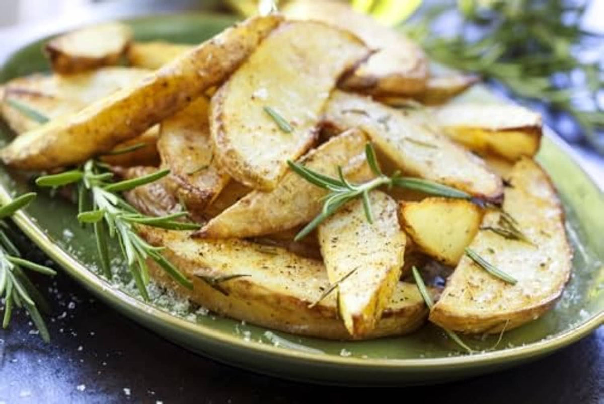 Roasted potato slices with herbs on a plate, sprinkled with sea salt