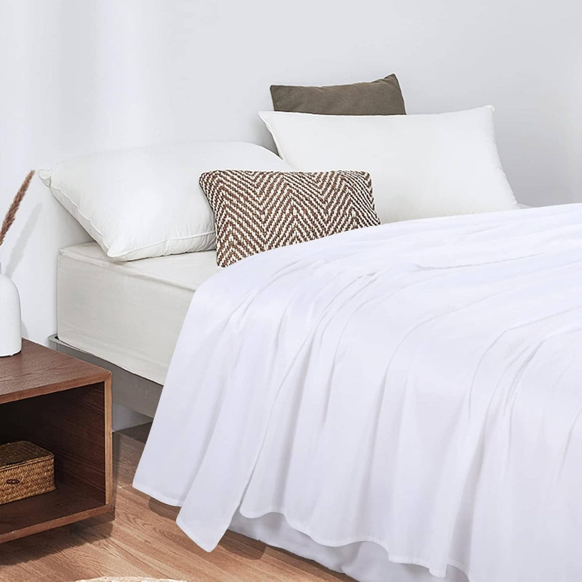 White flat sheet over a mattress with layered folds and a neat overhang