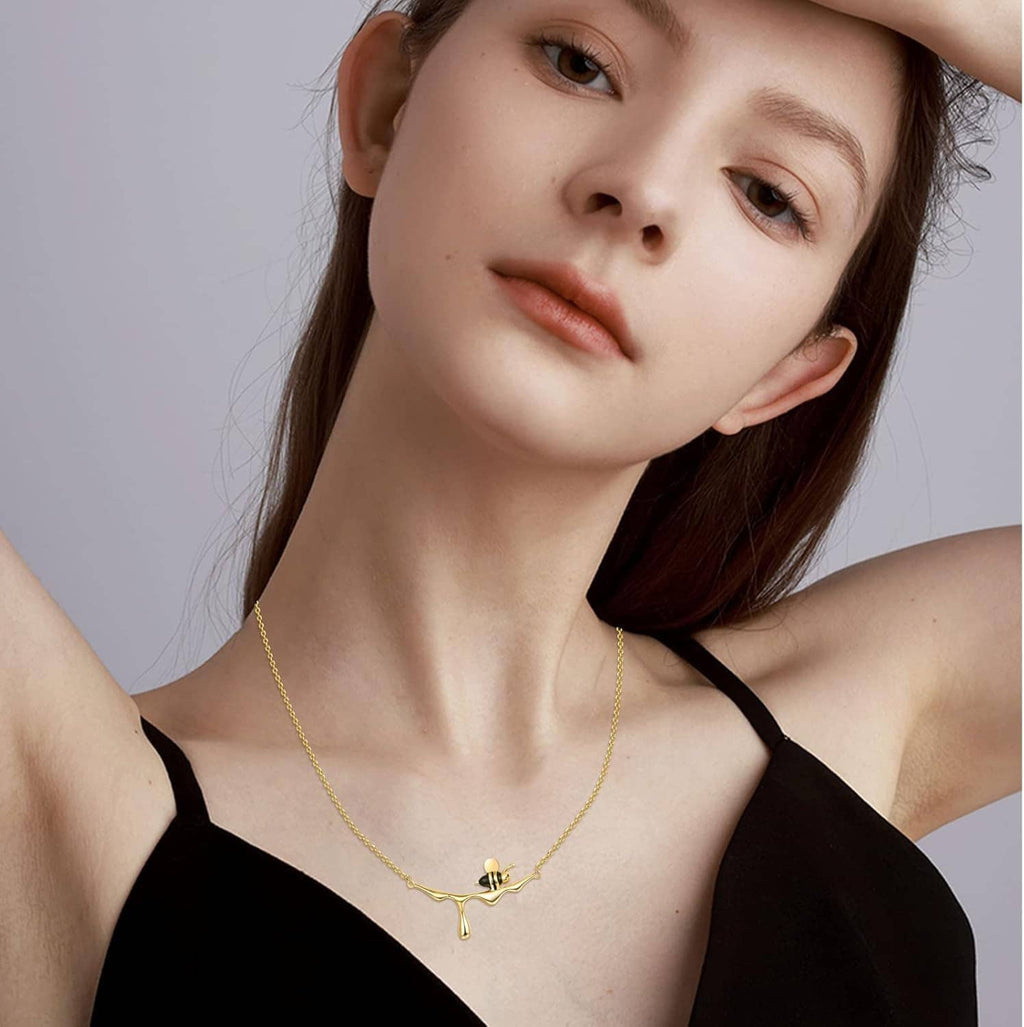 Gold-tone bee pendant necklace on a woman’s collarbone with thin chain