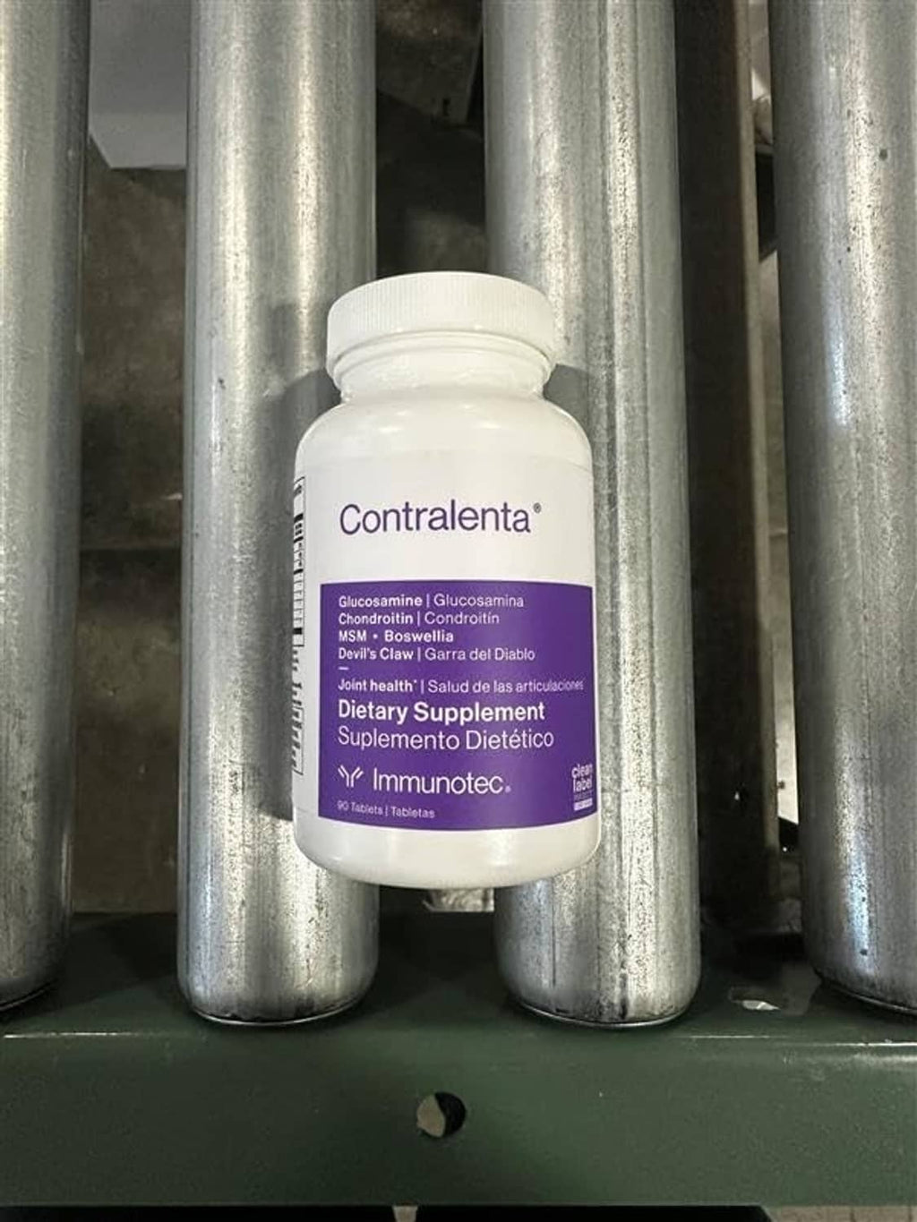 Dietary supplement bottle with label in front of silver canisters