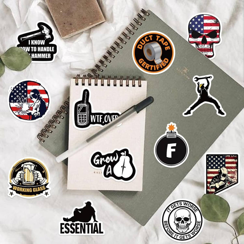 Assorted hard hat stickers with icons and sayings, scattered on notebooks and cards