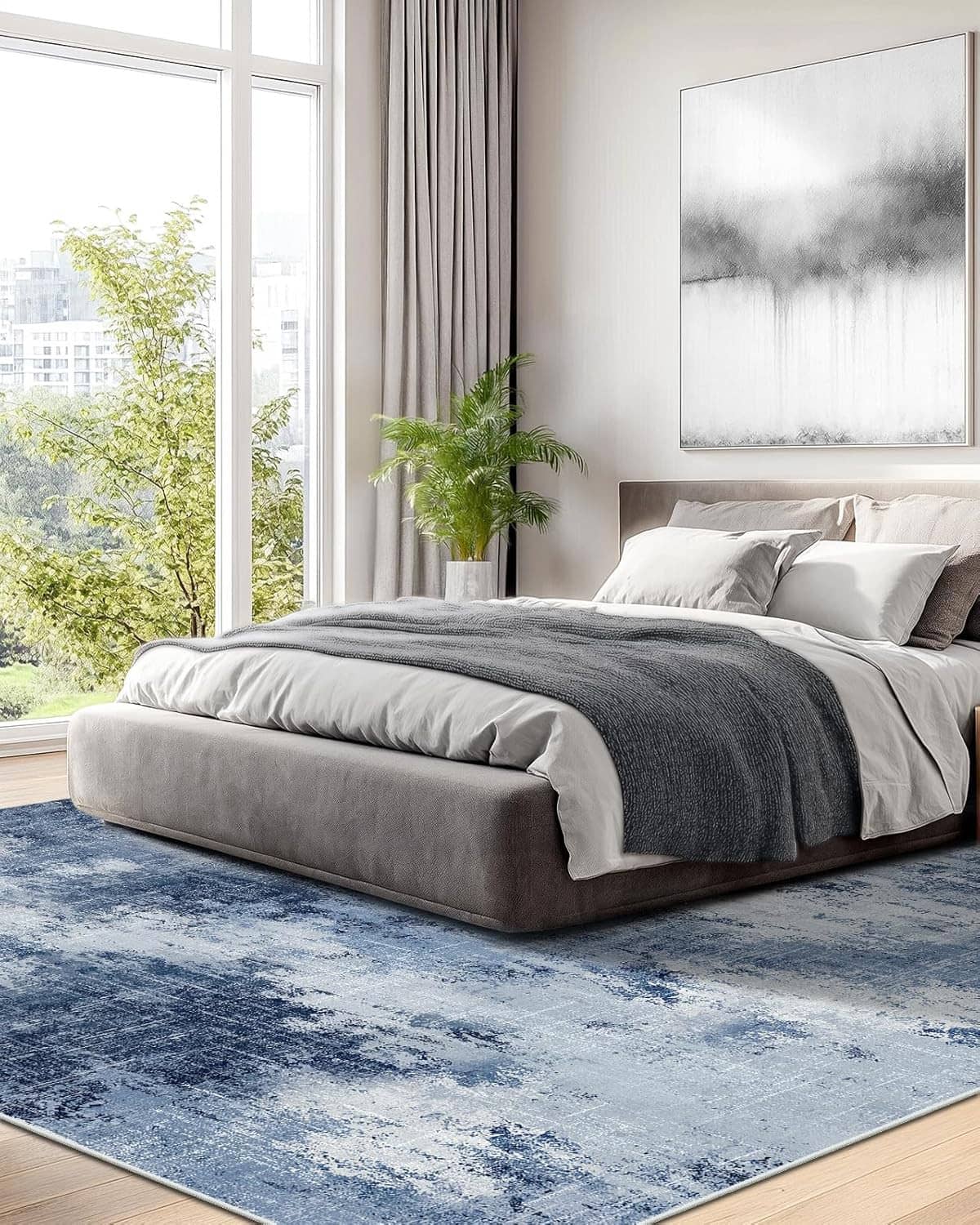 Blue abstract area rug in bedroom under bed with gray bedding