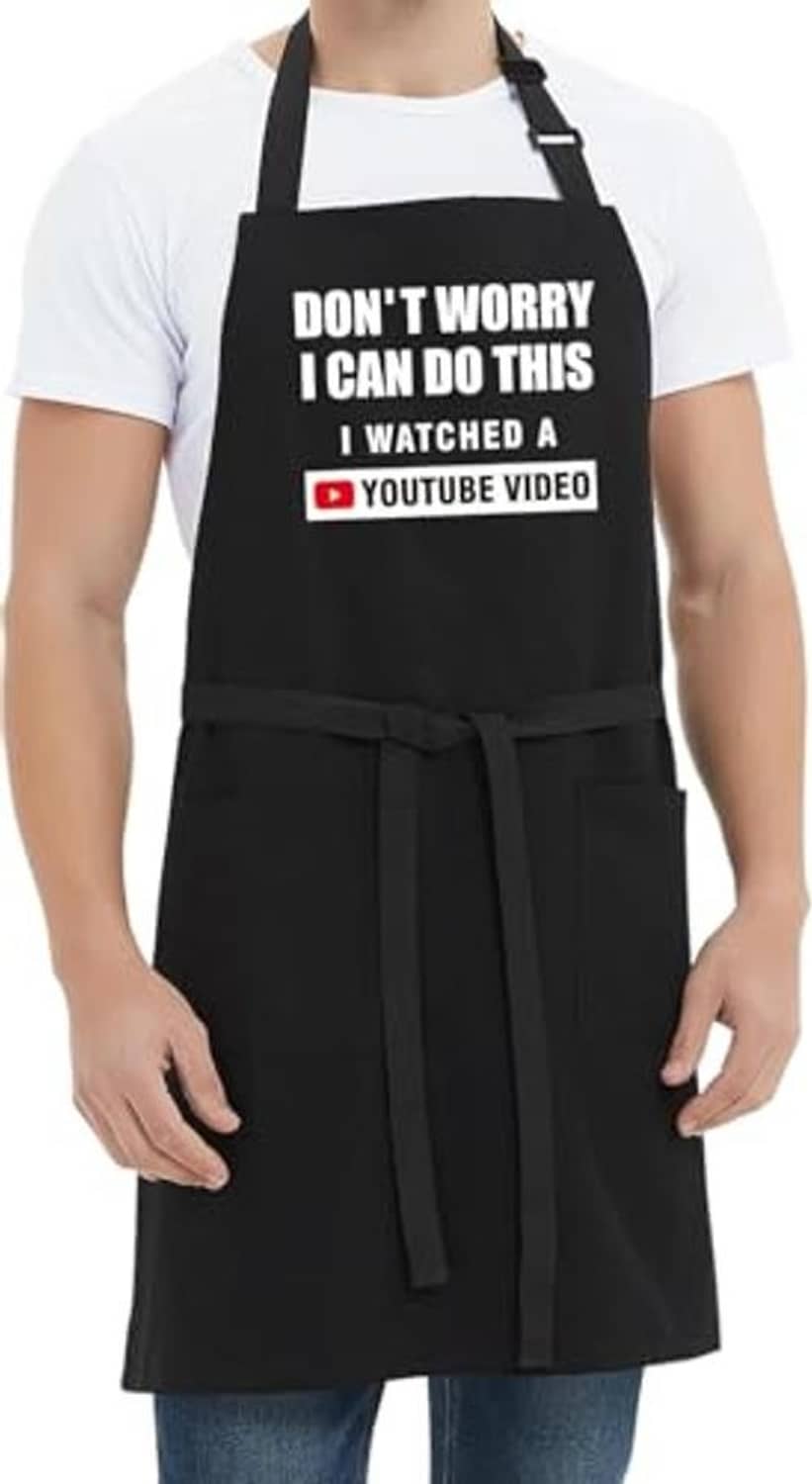 Black cooking apron with quote panel and tied waist, front view on model