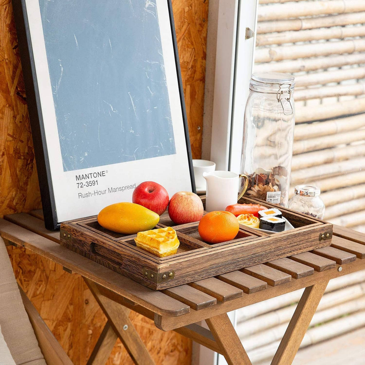 Rustic wooden serving tray with side handles holding fruit, cheese, and snacks