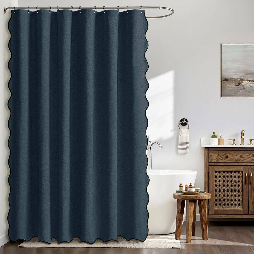 Navy blue scalloped shower curtain hanging over bathtub, pleated fabric panel.