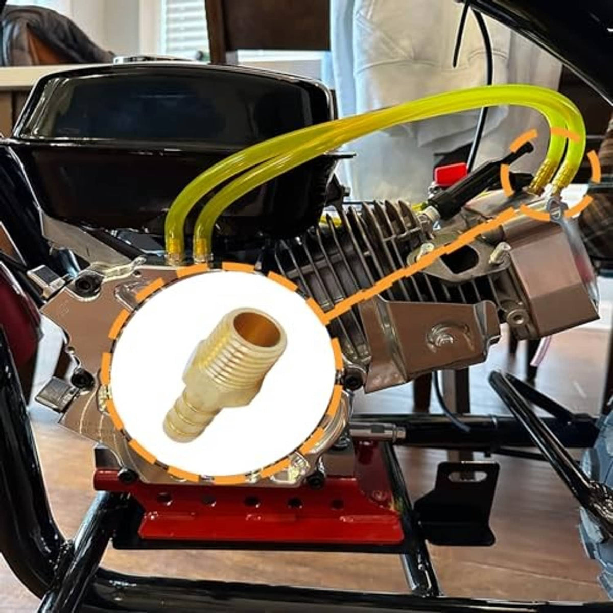 Brass hose barb fitting mounted on equipment with yellow hose and metal clamp