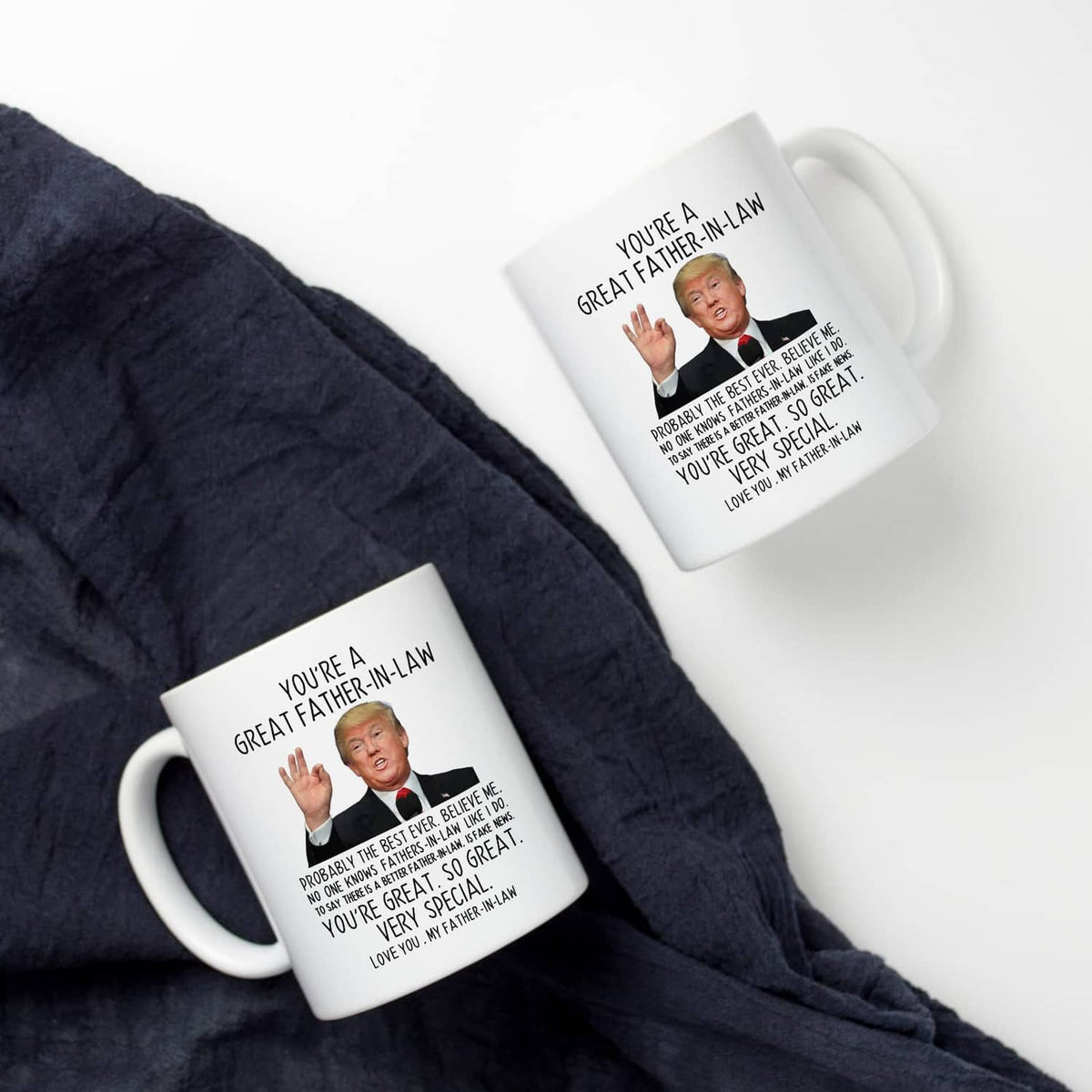 White coffee mugs on dark fabric, each with "Great Father-in-Law" printed text and portrait