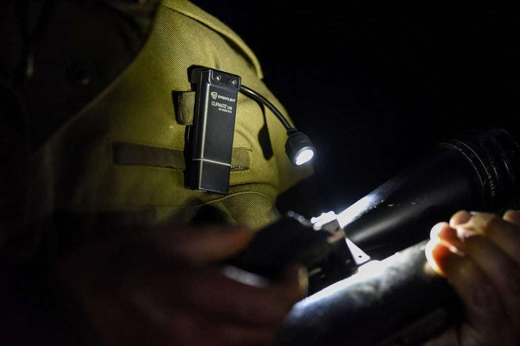 ClipMate light clipped to vest with flashlight beam directed forward in dark setting