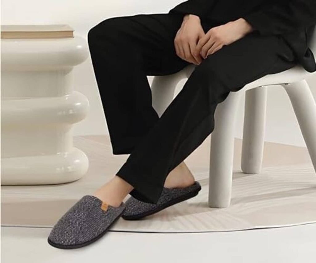 Men's slip-on house slippers in dark heather knit, worn with black pants