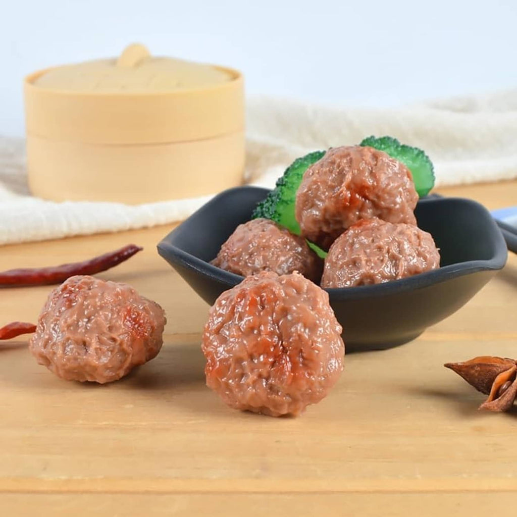 Artificial beef meatballs, brown, served in a bowl with green leaf garnish