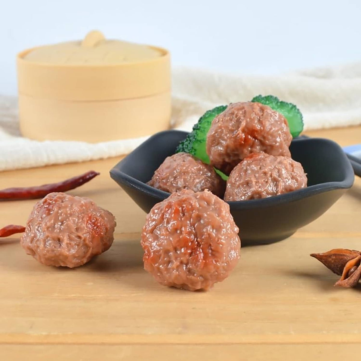Artificial beef meatballs, brown, served in a bowl with green leaf garnish