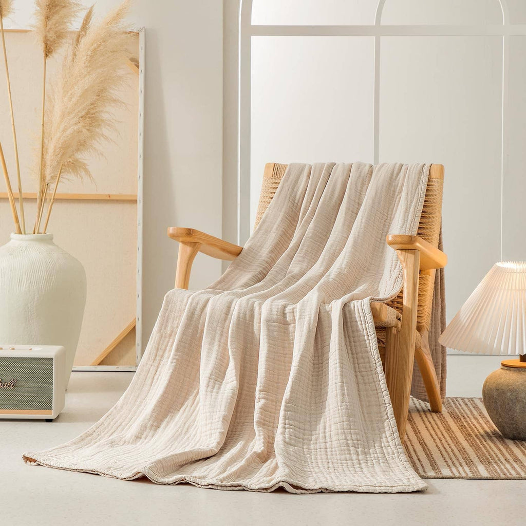 Cream muslin blanket spread over a chair with airy, crinkled layered fabric.