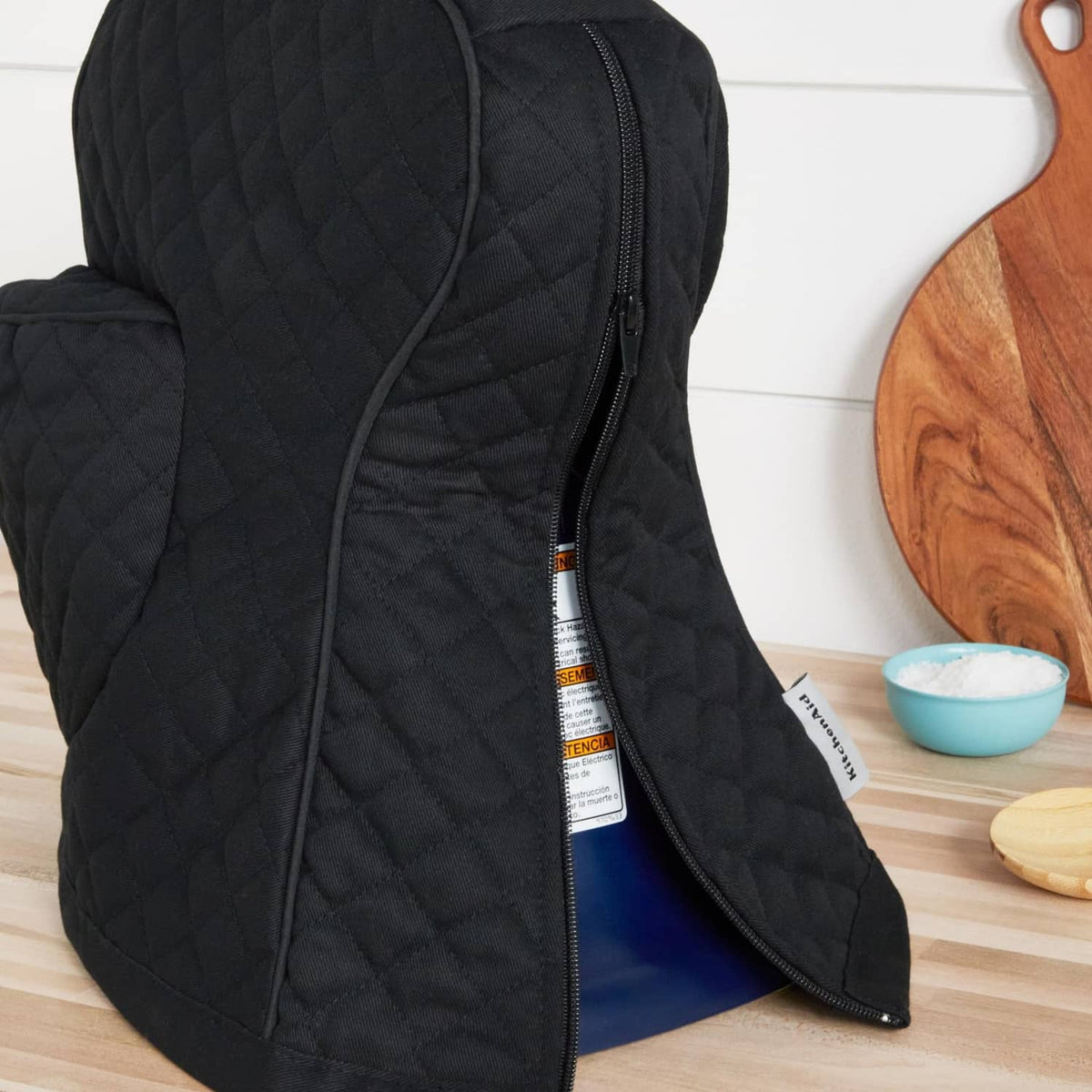 Black quilted stand mixer cover with open zipper and blue-lined interior