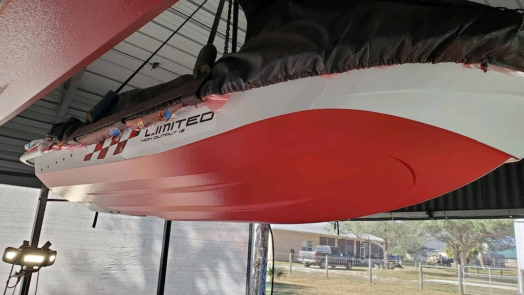 Red boat hull underside with outboard stern, under canopy