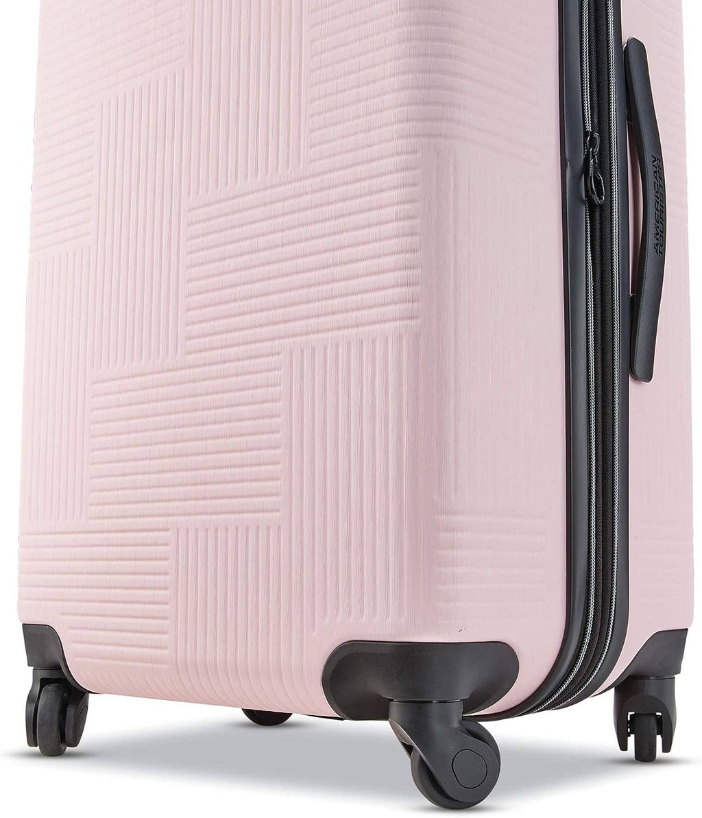 Pink hard-shell luggage corner view with four spinner wheels and black trim