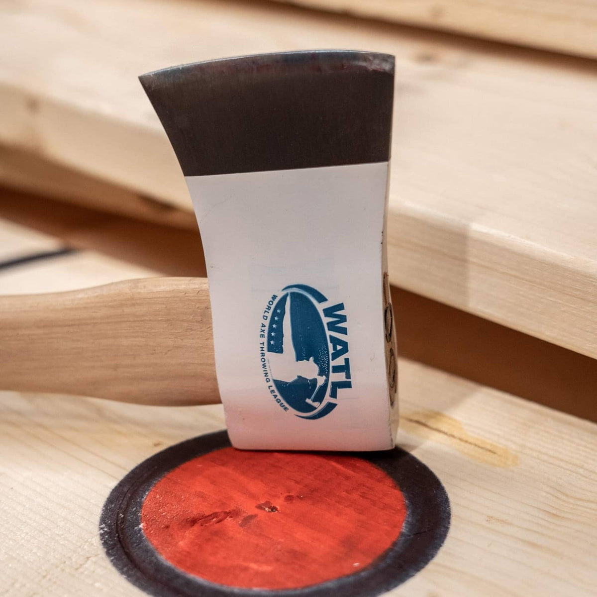 WATL-logo axe planted near a red target disc on light wood