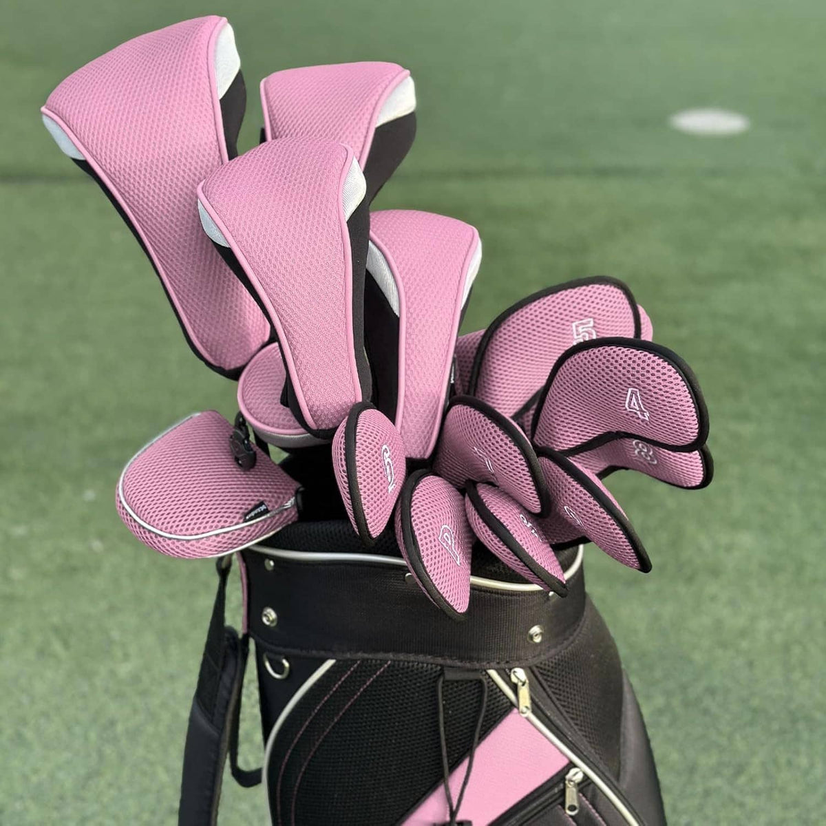 Set of pink mesh golf head covers with black long necks and numbered sizes