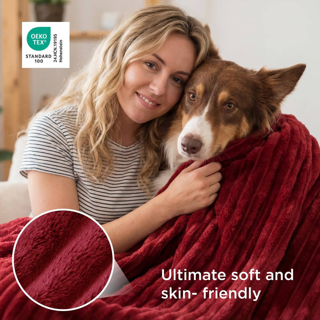 Red sherpa-style blanket with ribbed texture beside dog and woman holding blanket