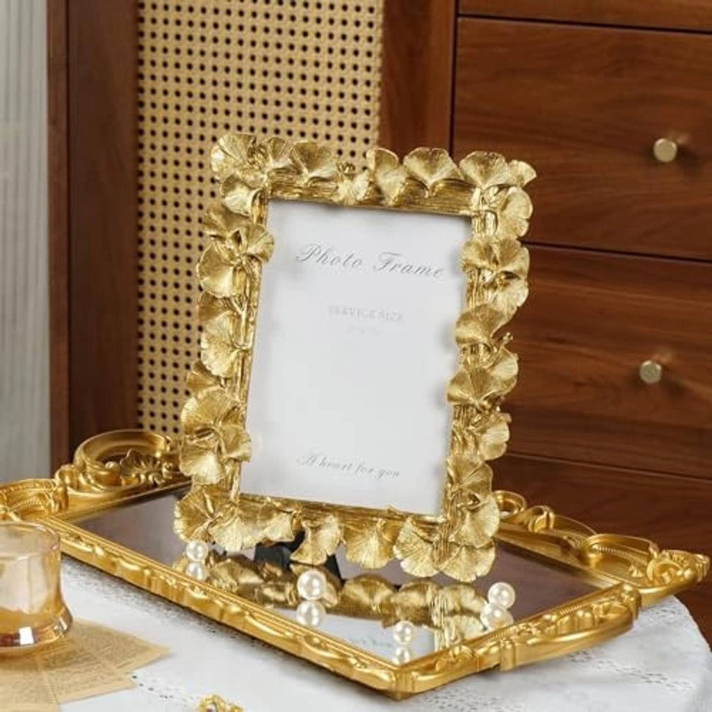 Gold ginkgo-leaf photo frame standing on tabletop, ornate leaf border