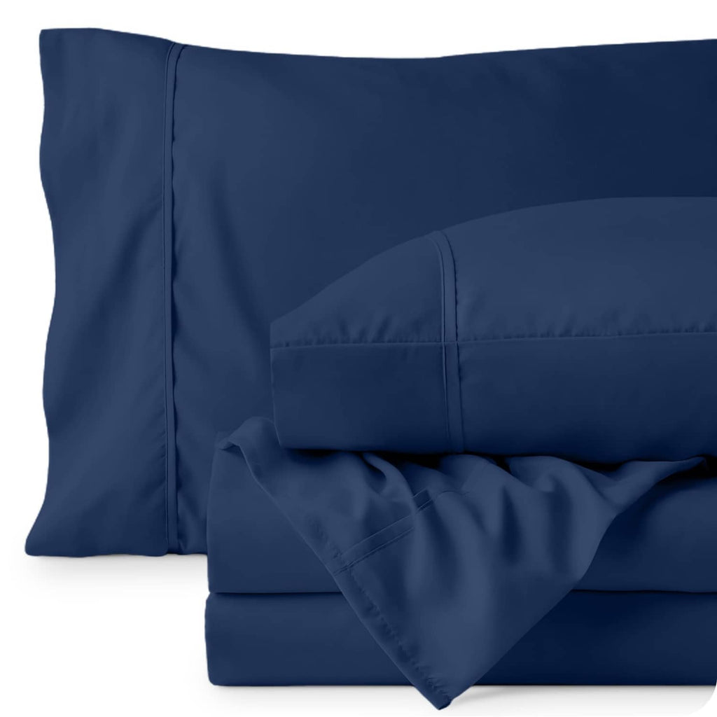Dark blue pillowcase and fitted sheet close-up with stitched seams on white background