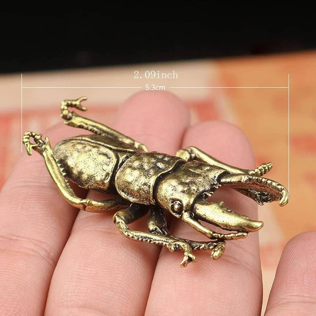 Miniature brass beetle ornament lying on hand, detailed legs and antennae