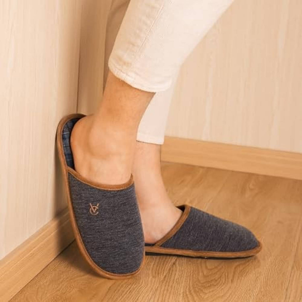 Dark gray knitted slip-on slippers with brown trim and blue plaid lining on stairs