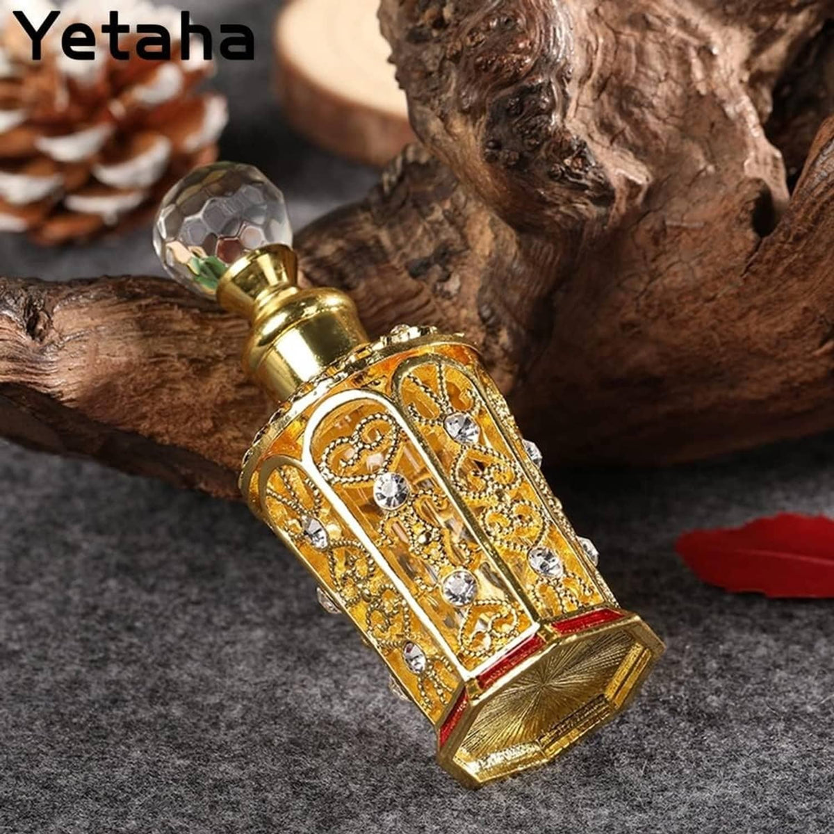 Golden jeweled perfume bottle with faceted crystal cap and red base on ornate metal body
