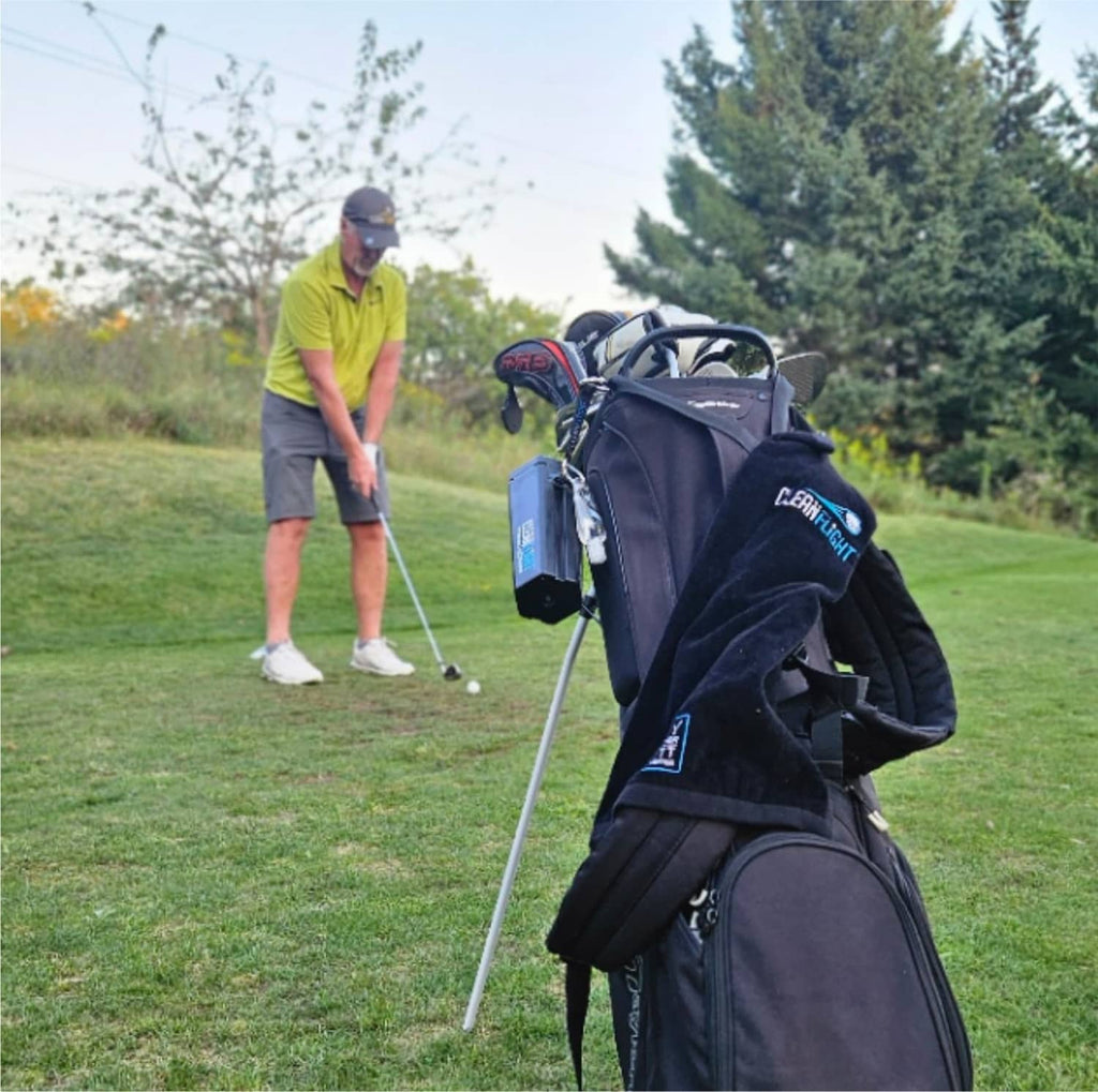 Clean Flight golf ball washer attached to a dark golf bag with blue front label