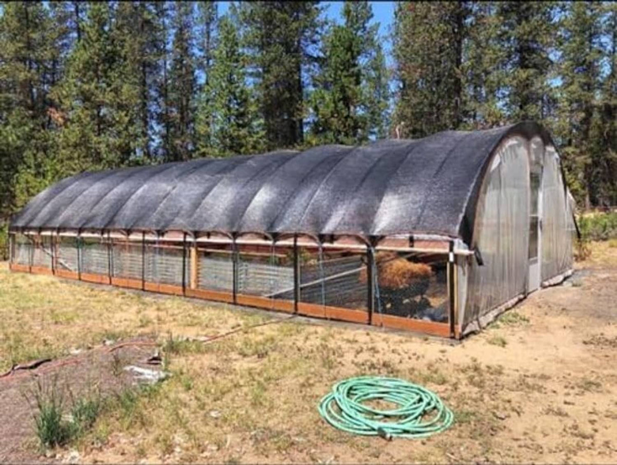 Outdoor shade mesh tarp installed over a greenhouse-style frame
