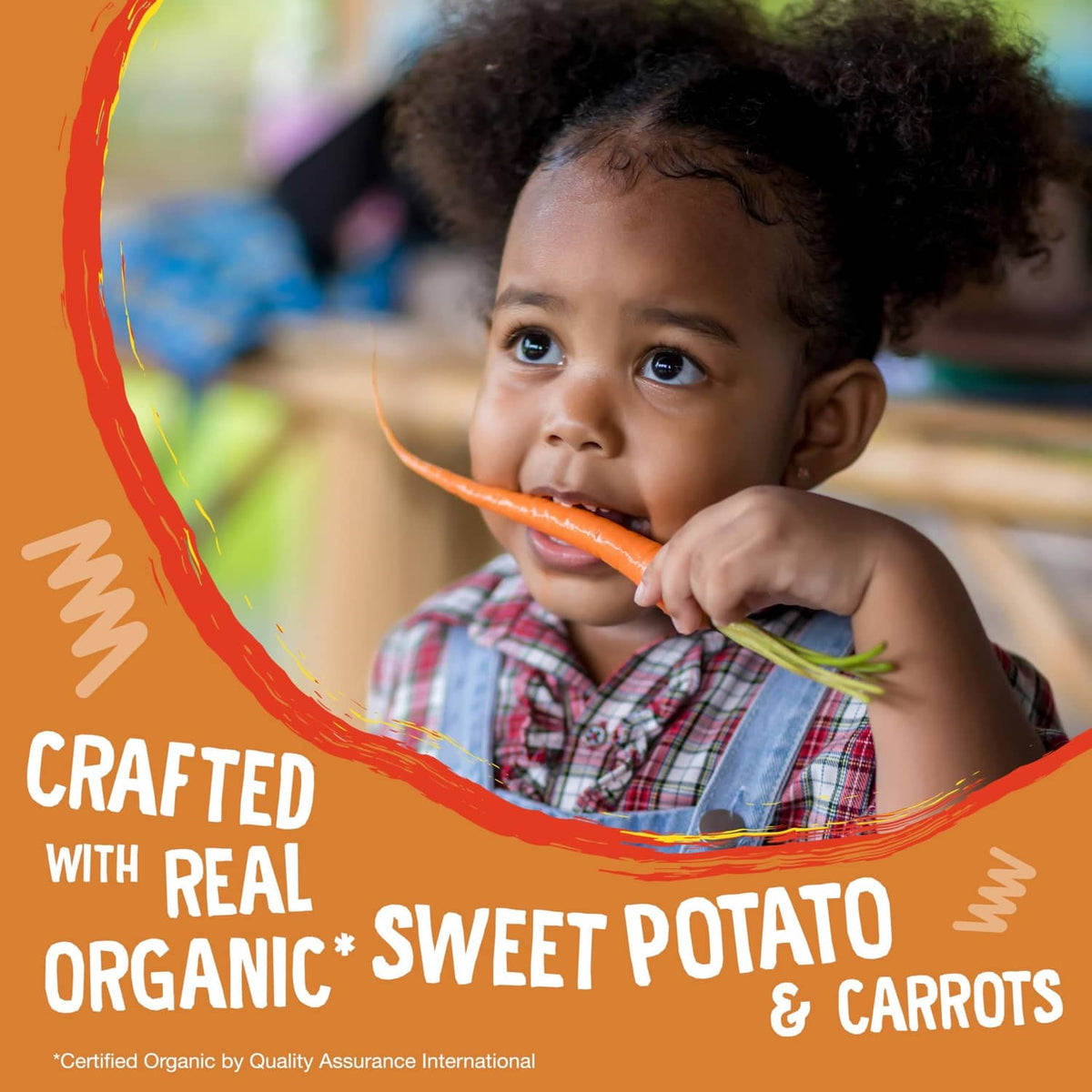 Toddler eating an orange carrot snack bar, sweet potato and carrots theme