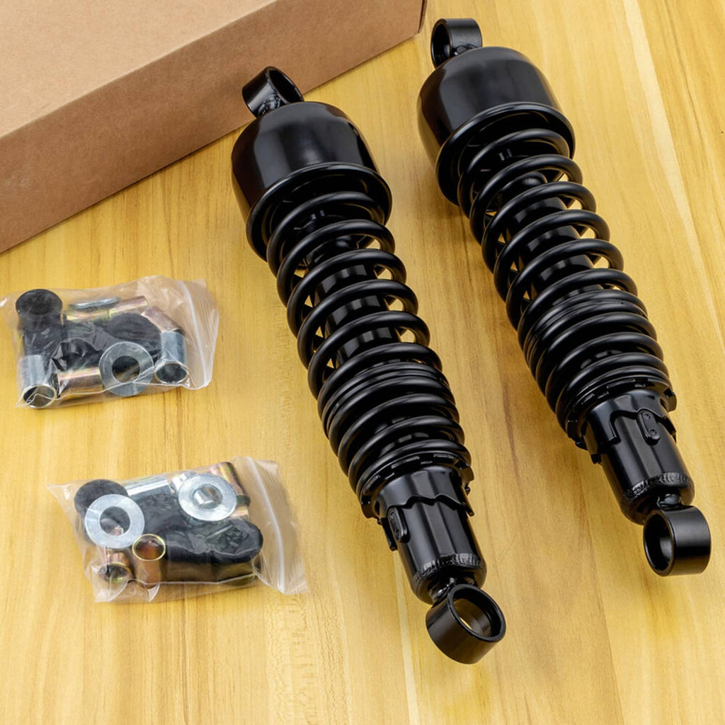 Pair of black rear shocks with coil springs and loose hardware on a work surface