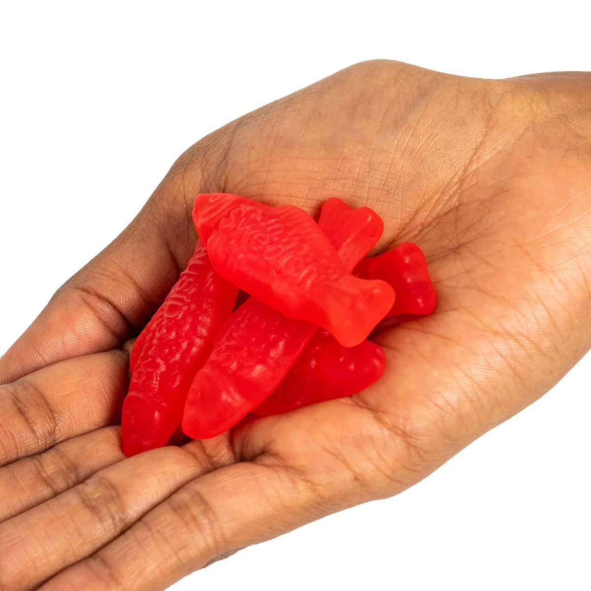 Hand holding red gummy fish candies