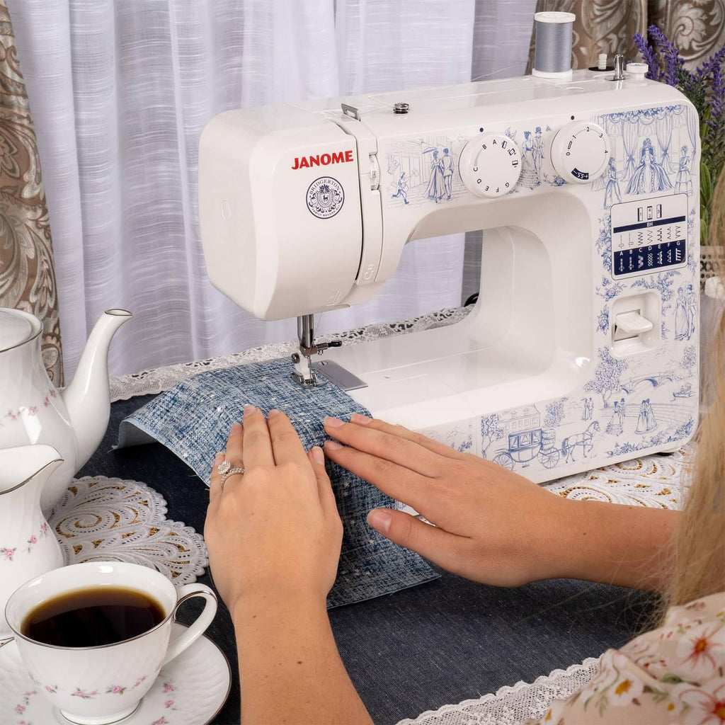Janome sewing machine in use, hands guiding blue fabric under the needle