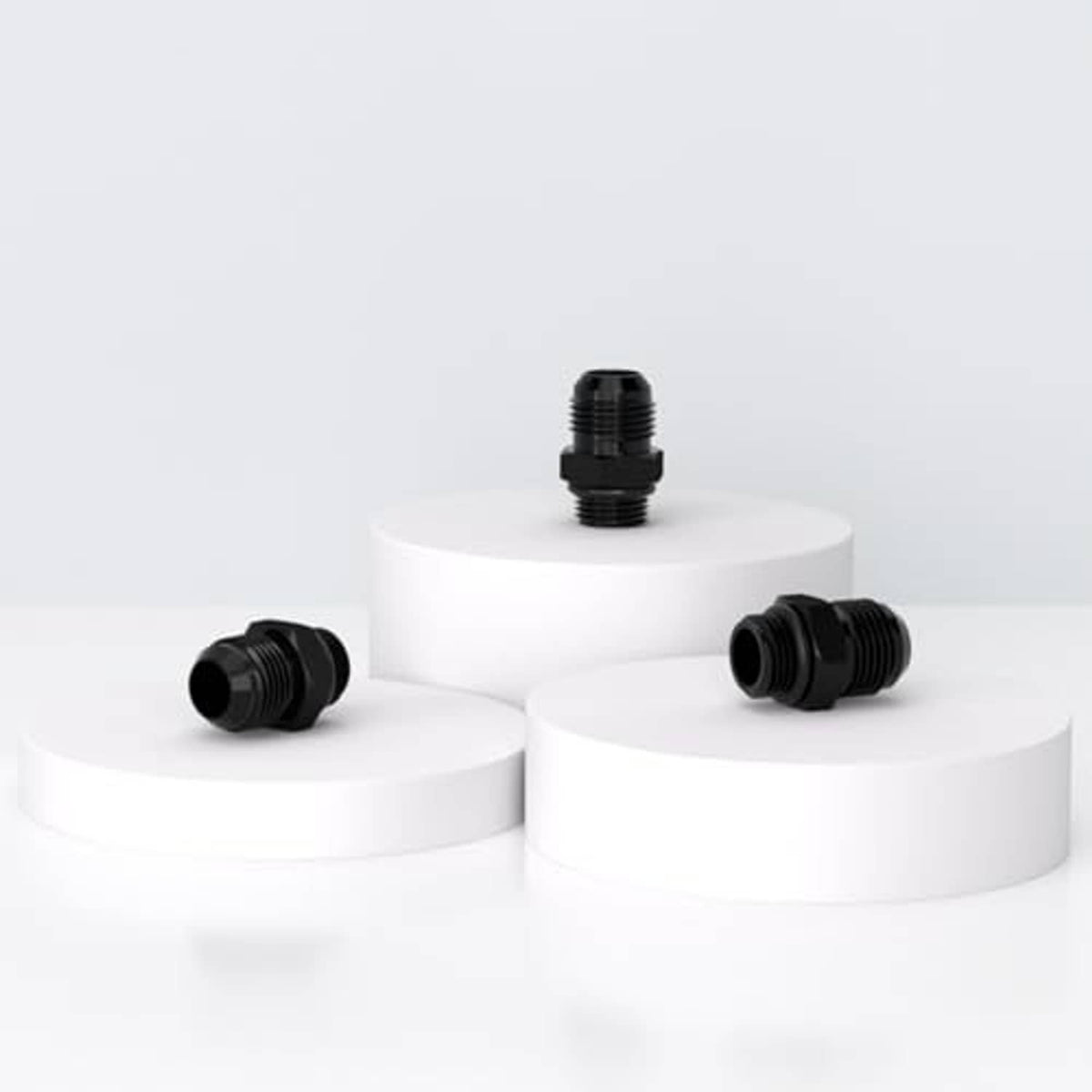 Black AN-style hose fitting adapter set on display blocks, threaded ends visible