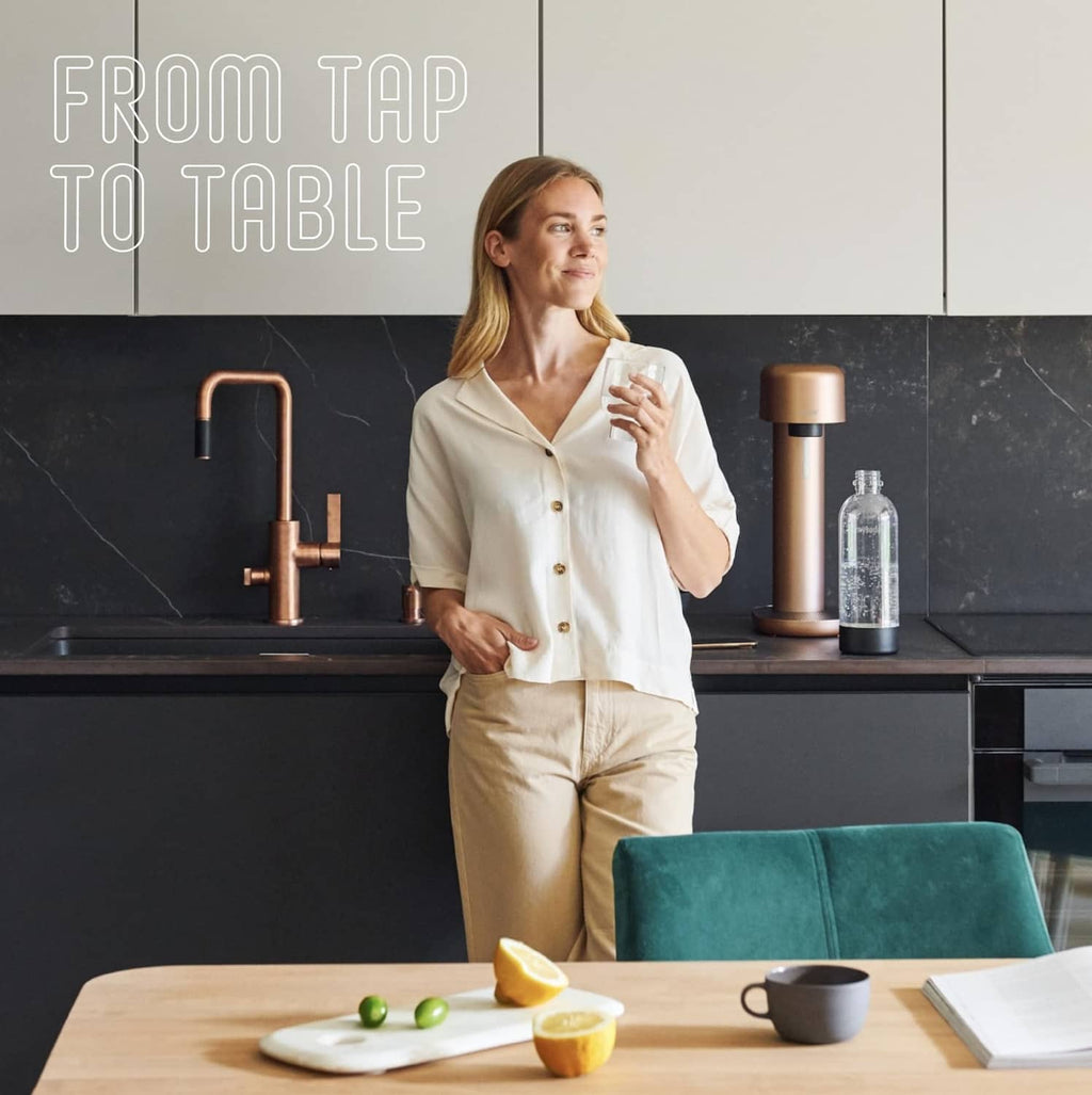 Mysoda carbonating bottle with black cap in hand, on kitchen counter