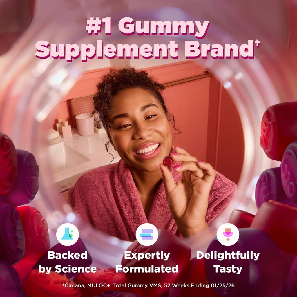 Woman holding a gummy near a supplement container, smiling in a kitchen setting