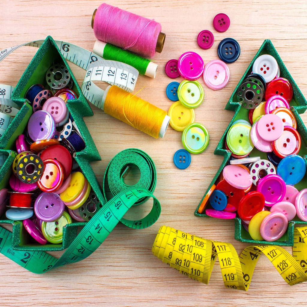 Colorful round resin buttons around thread spools and measuring tape on wood.