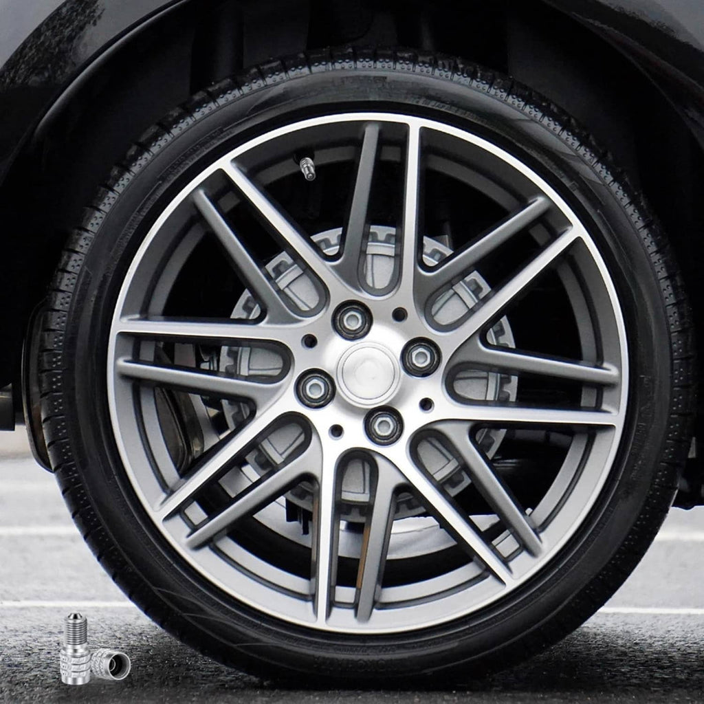 Silver tire valve stem cap lying near a wheel and tire